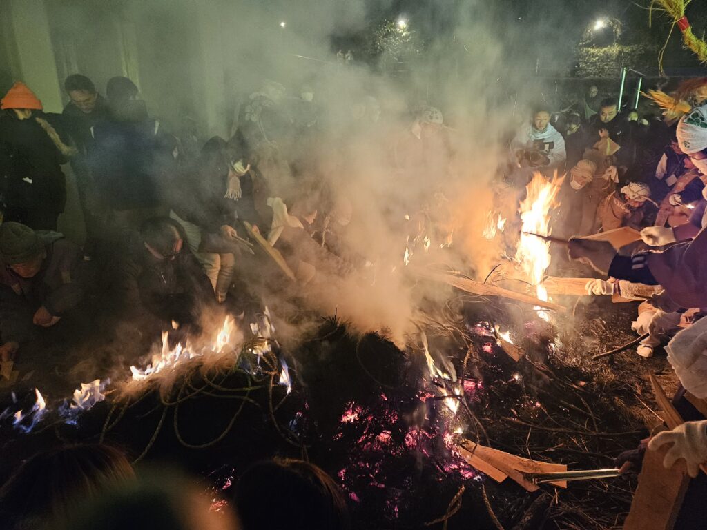2026年1月7日の太宰府天満宮春の神事、鬼すべ神事の後に観光客たちが木片を火にくべている様子