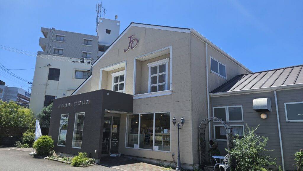 2026年7月10日に訪れた大宰府の有名菓子店「ジャンドゥ」の外観。
真夏の青空の下、白く直線的な機能美あふれる建物が建っている。